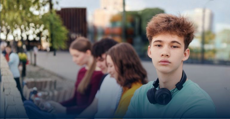 a teenage boy looking into the camera wearing headphones around his neck