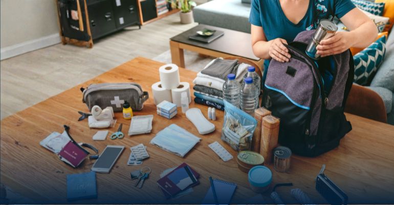 Hands packing a backpack with emergency supplies