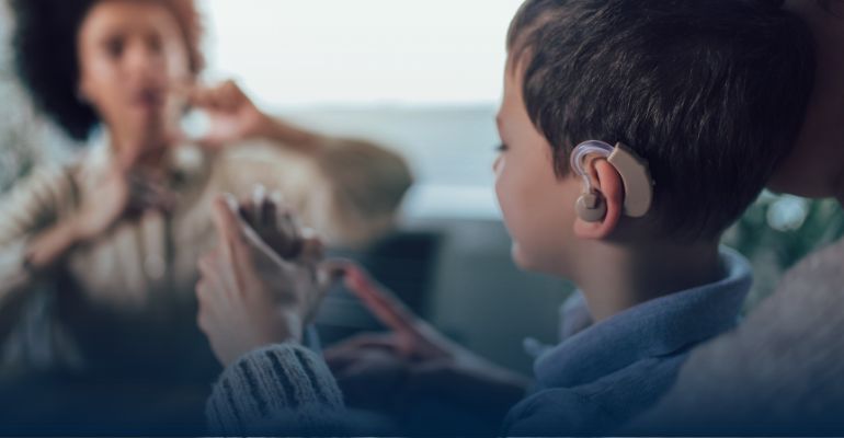 women using signlanguage to boy with hearing aide