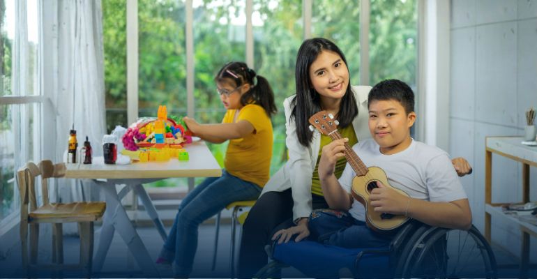Boy in wheelchair with adult playing a guitar