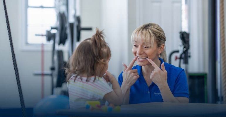women pointing to her face and smiling at little girl
