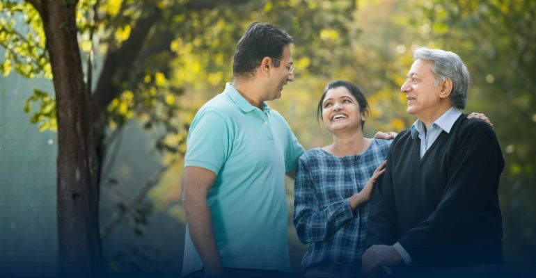 Man and women smiling while hugging a third older man