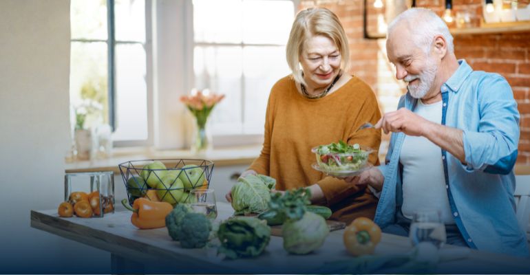 Man and women prepare a salad in a kitchen