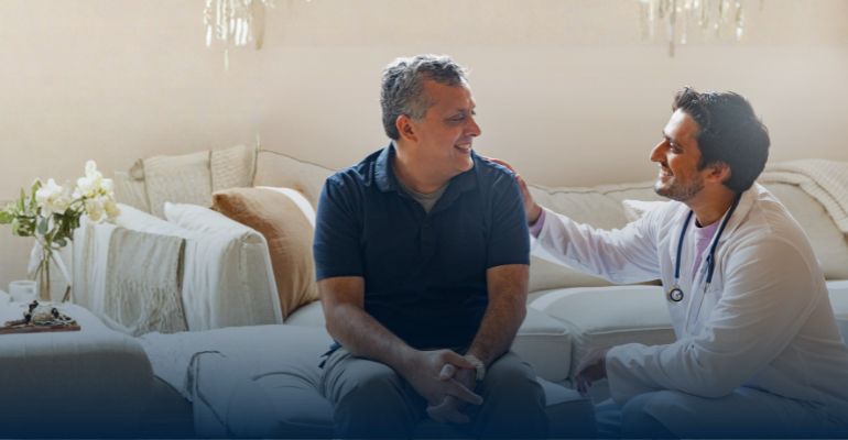 A docter sitting next to a male patient smiling